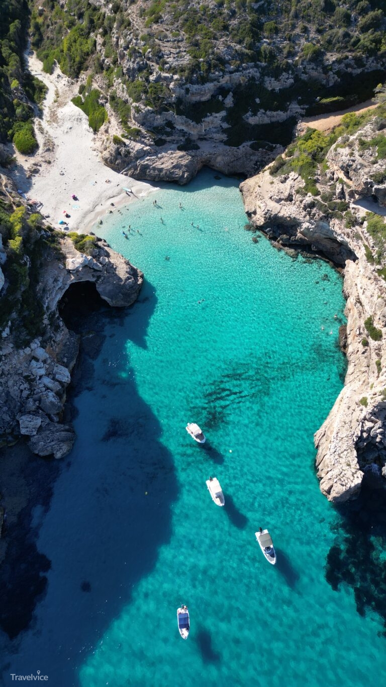 Blick aus der Luft auf Boote und Badegäste im türkisblauen Wasser der Cala Màrmols