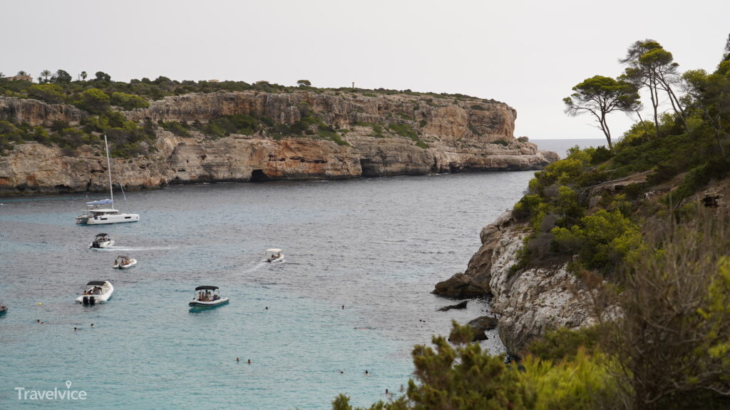 Caló des Moro mit Badegästen am schmalen Strand und Booten vor der Küste