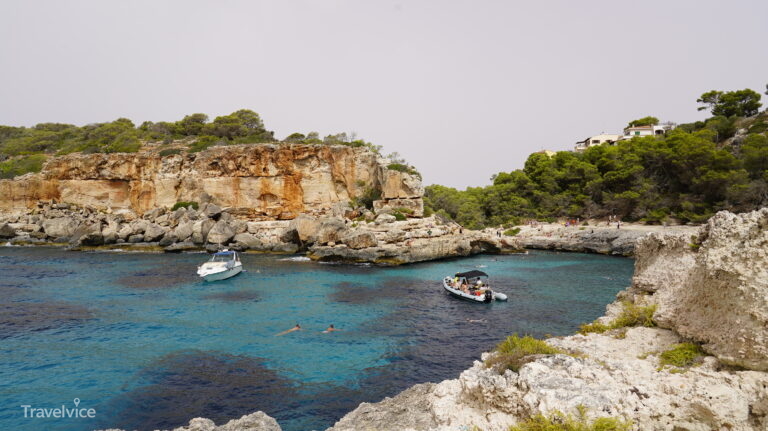 Felsige Bucht Cala s’Almunia mit Booten auf klarem Wasser