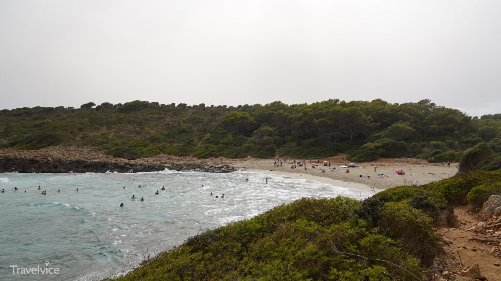 Sandstrand und klares Wasser in der von Felsen eingerahmten Cala Varques