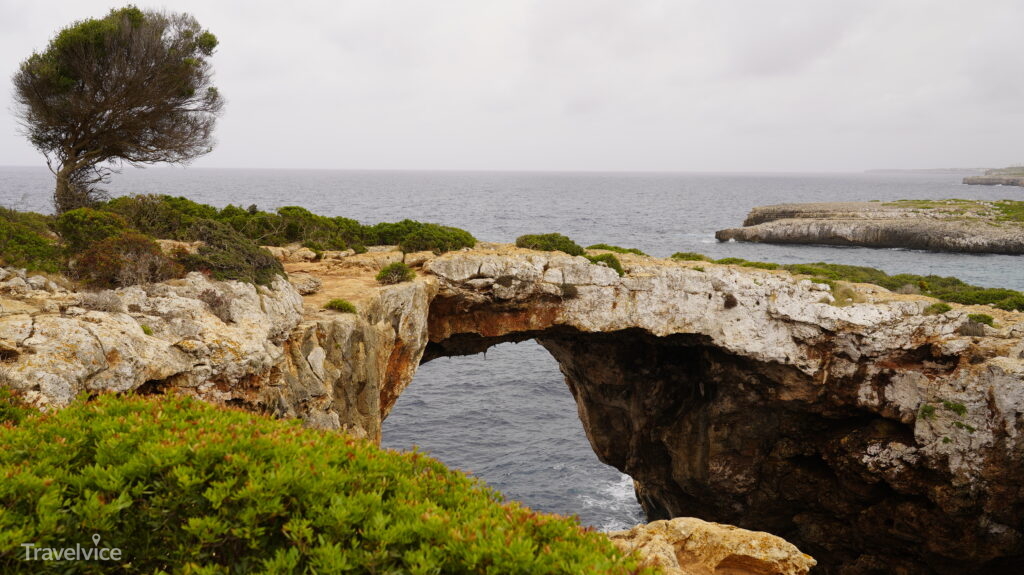 Natürliche Felsbrücke über dem Meer an der Küste bei Cala Varques