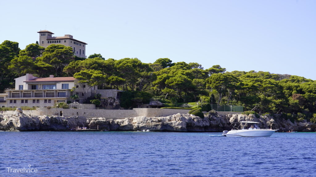 Küstenblick vom Boot bei Cala Rajada mit einer Villa über den Felsen