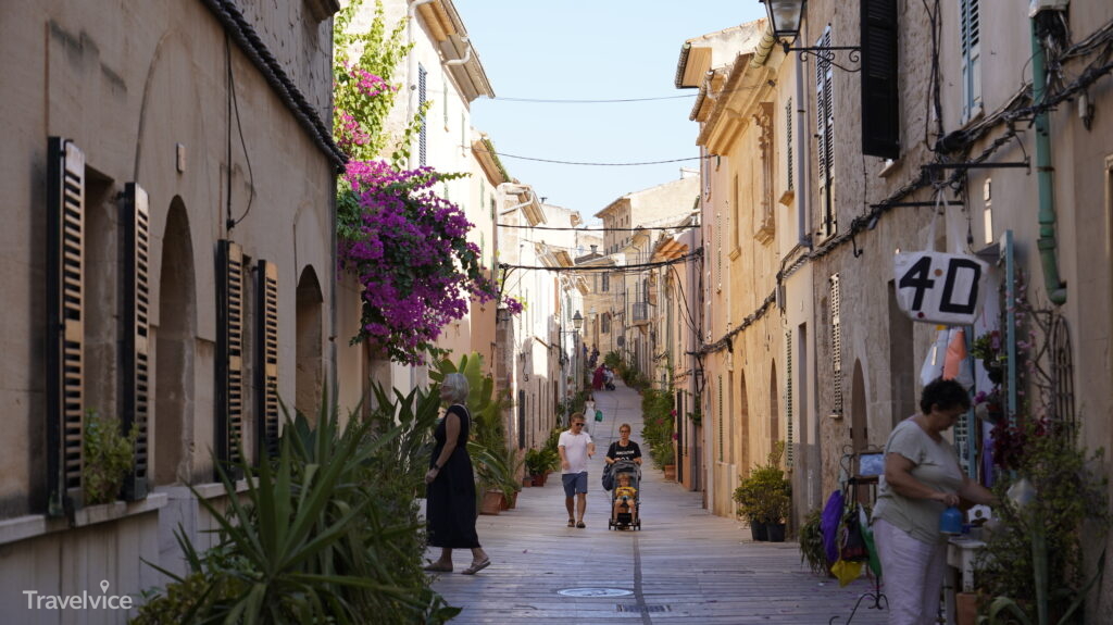 Bougainvillea über einer Gasse zwischen den Steinhäusern von Alcúdia